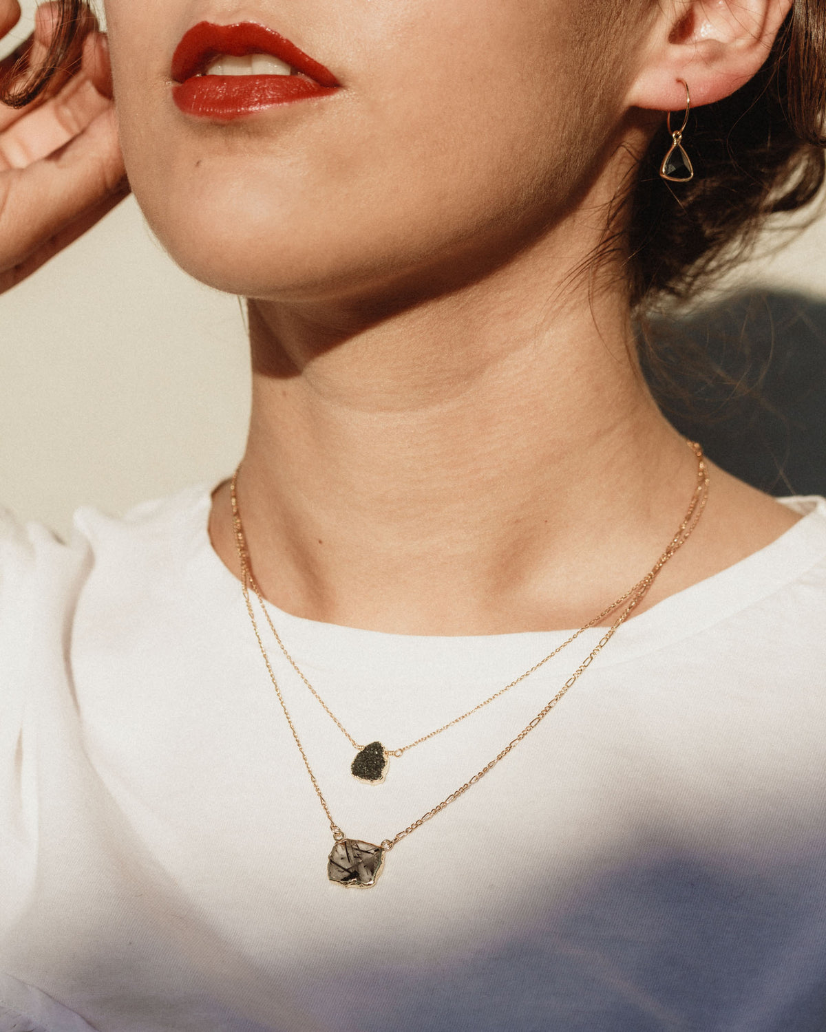 Model wearing Spellbound necklace with black druzy and marbled white stone and black earrings