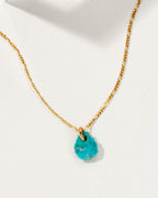 Flower Petal Necklace with a turquoise gemstone charm and gold chain.