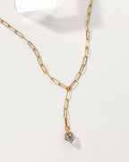 Gold Wild Thing necklace with a small crystal on a white background.