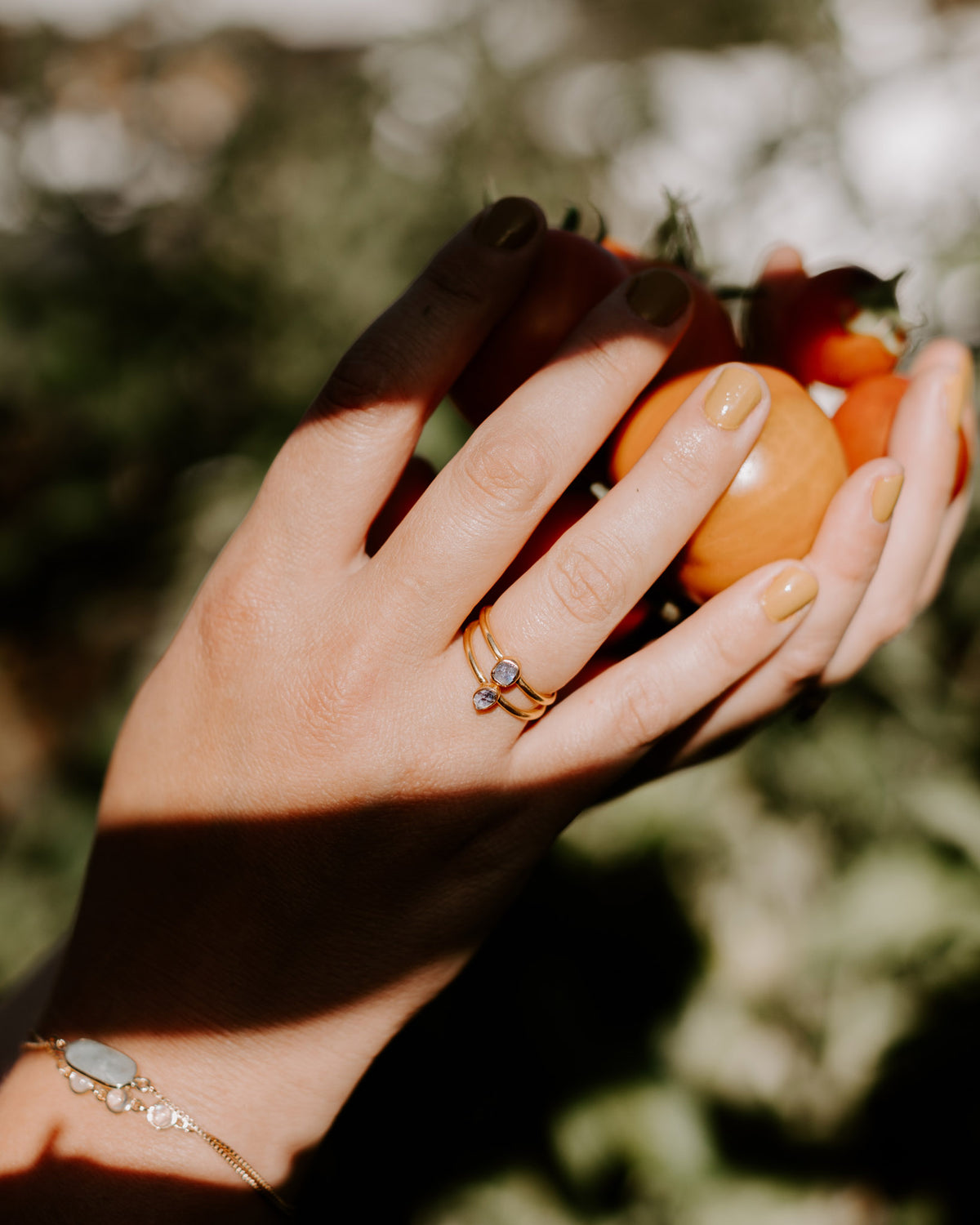 Double banded gold Firefly Labradorite Ring on a hand holding orange tomatoes.