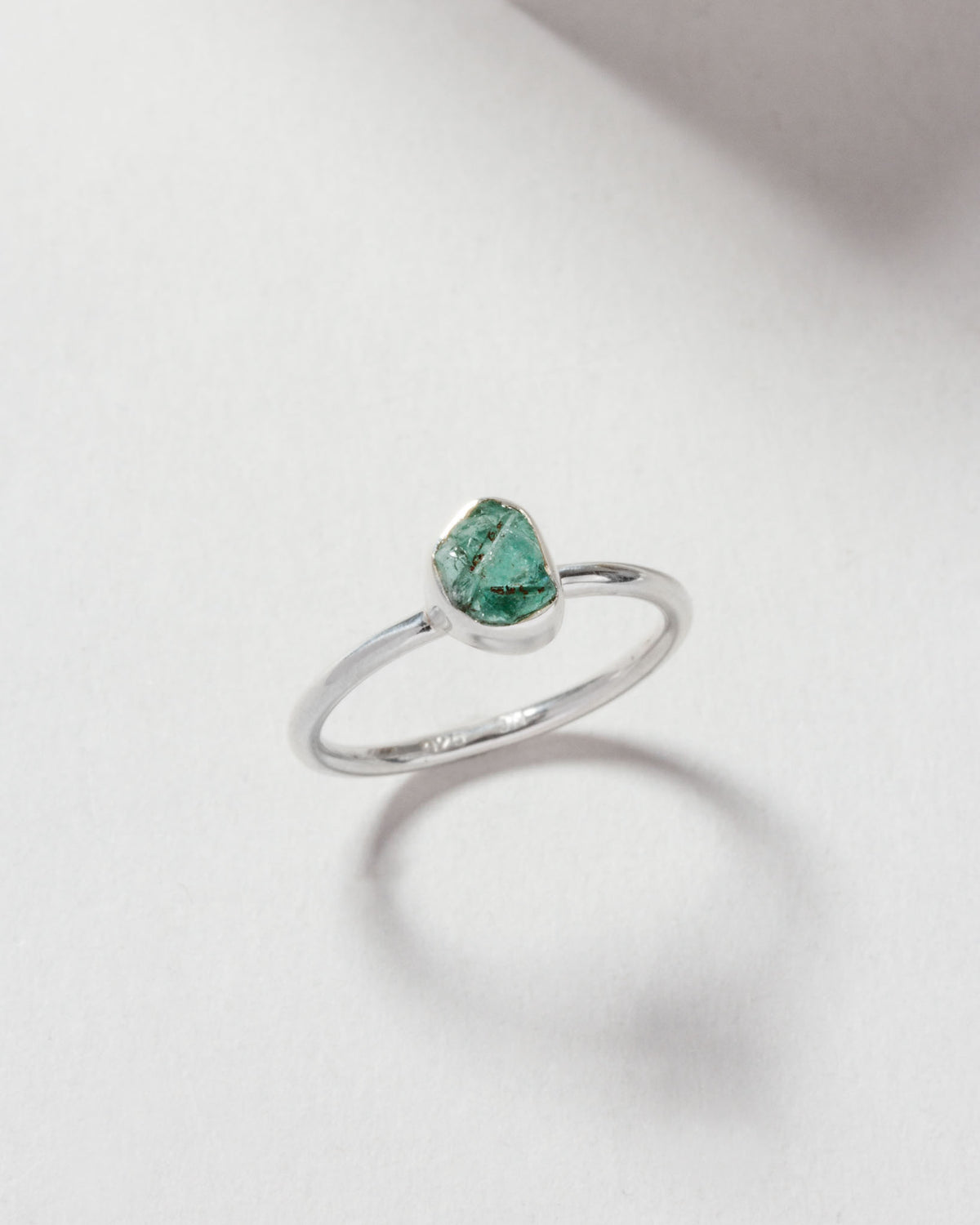 Silver ring featuring a raw-cut emerald gemstone.