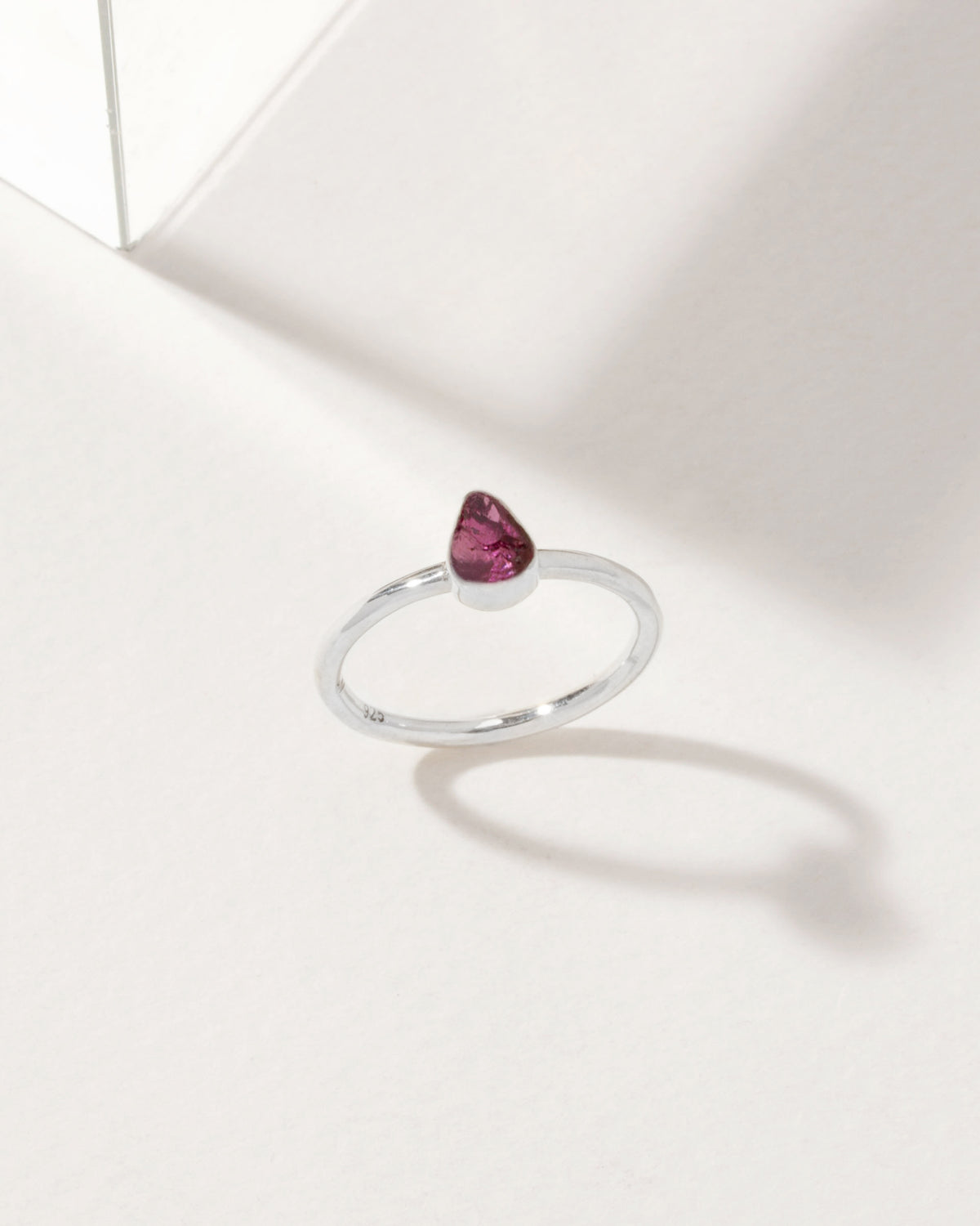 Silver ring featuring a Rhodolite Garnet gemstone on a white surface.