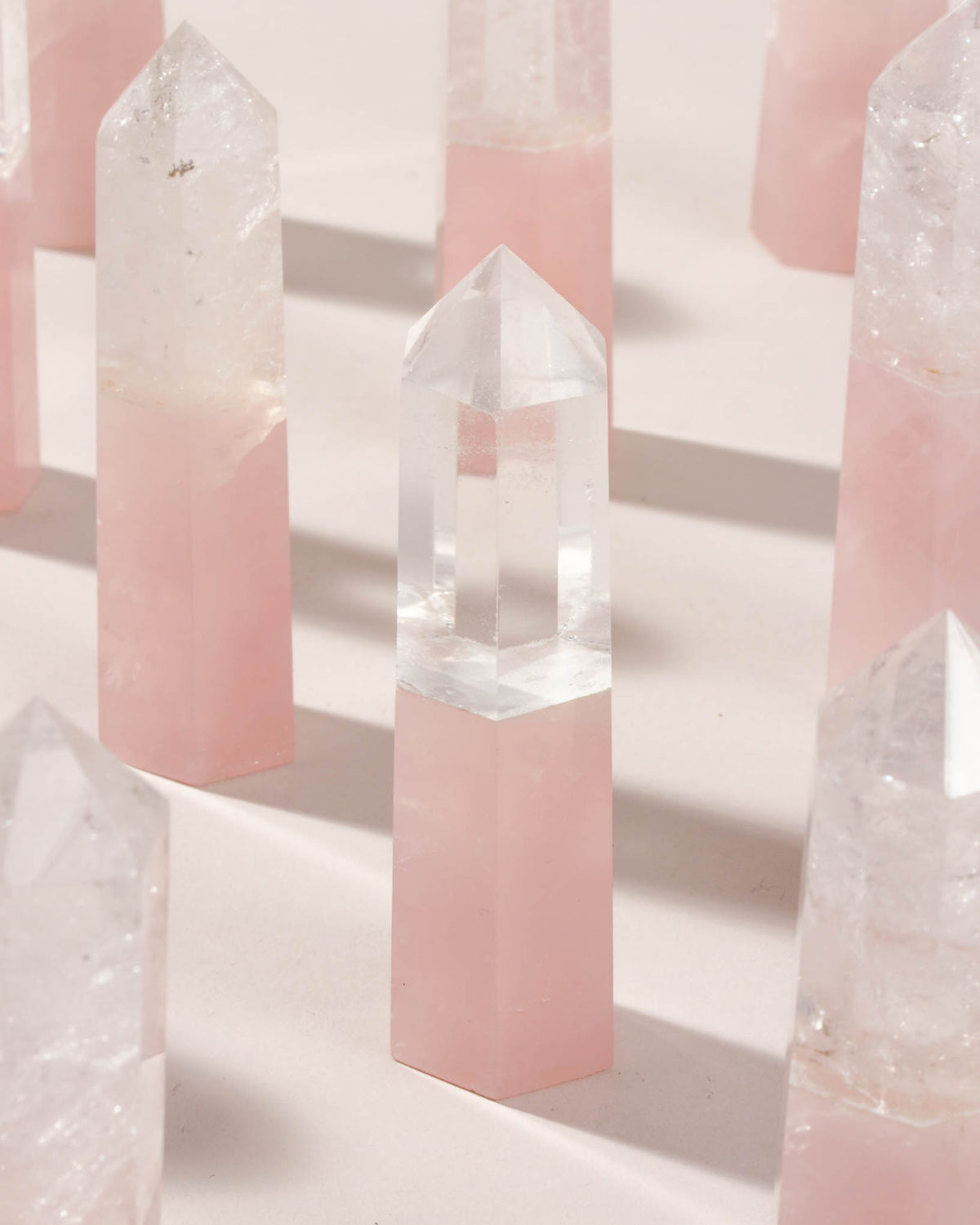 Rose Quartz and Clear Quartz crystal towers are displayed on a light surface.