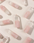 Rose Quartz and Clear Quartz crystals are scattered on a light surface.