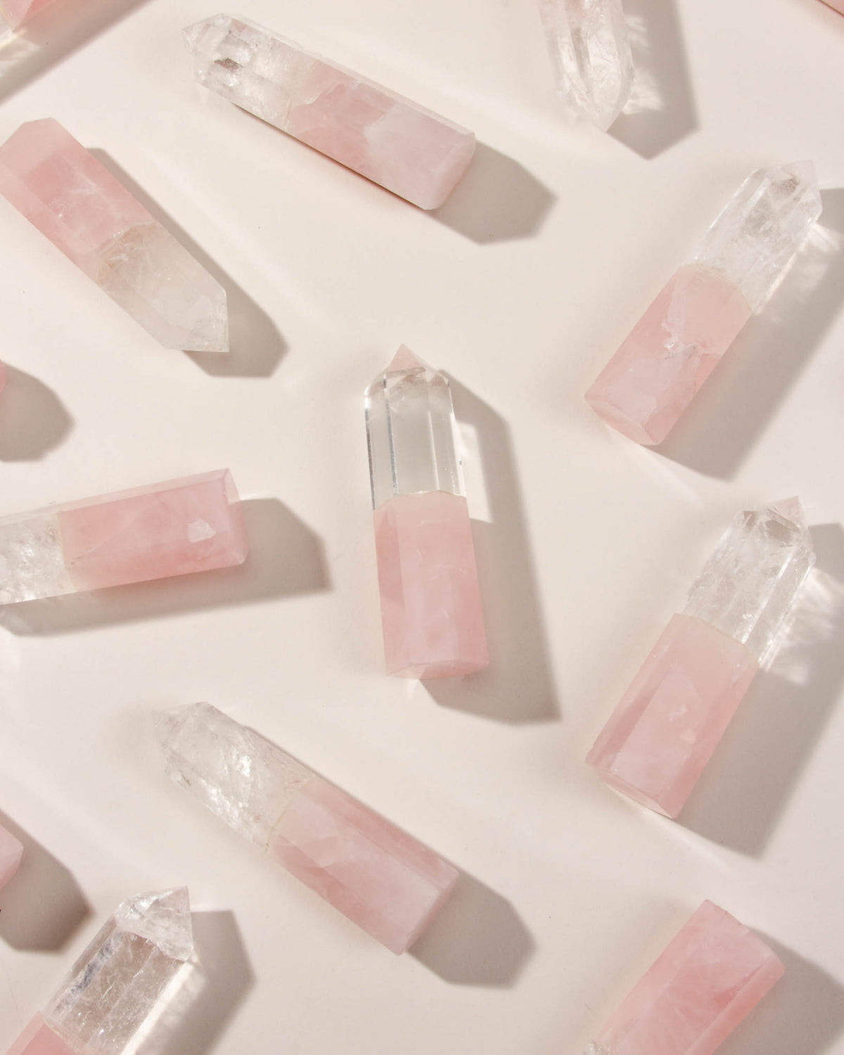 Rose Quartz and Clear Quartz crystals are scattered on a light surface.