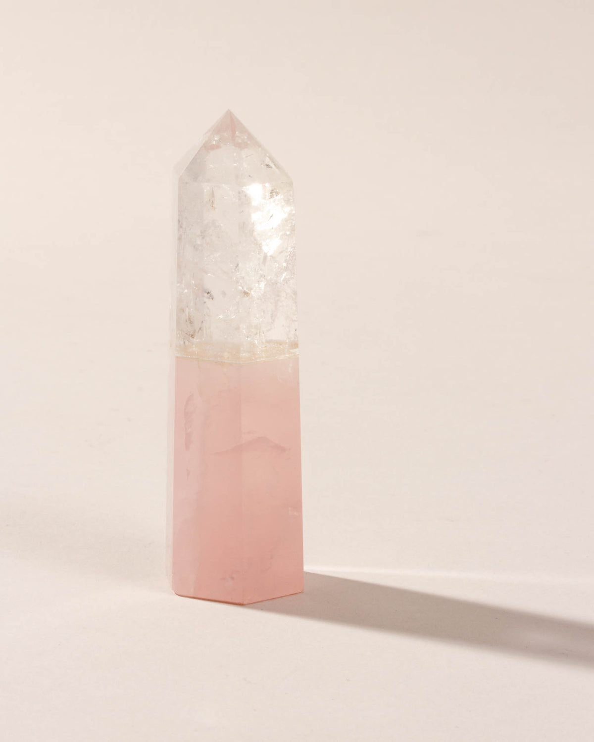 Rose Quartz and Clear Quartz crystal obelisk on a light background.