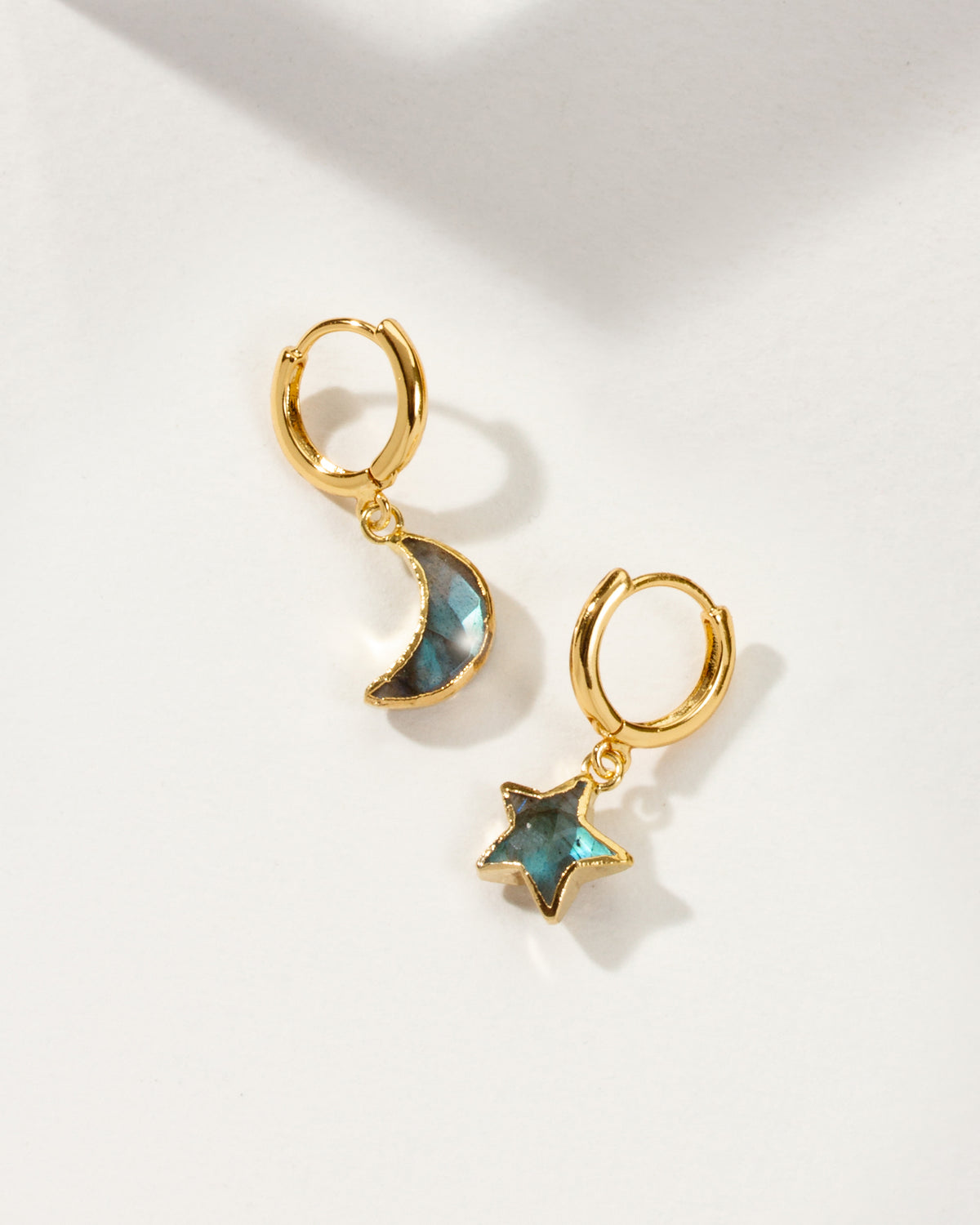 Pair of mismatched gold huggie hoop earrings with labradorite star and moon charms