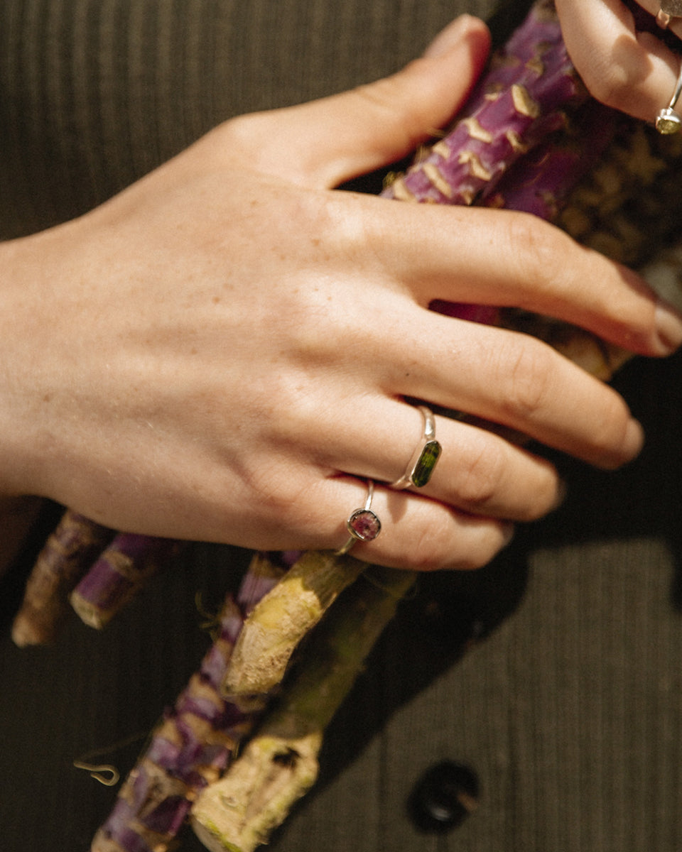 Hand holding vegetables while wearing silver watermelon tourmaline and green gemstone rings