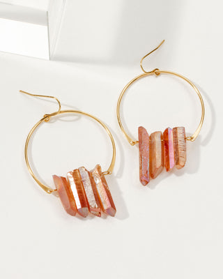 Pair of Peach Quarts Supernova earrings with gold hoops on a white tabletop.