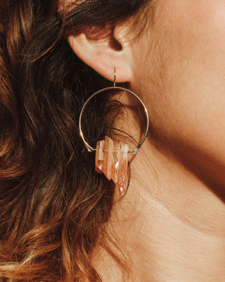 Closeup of model wearing Peach Quartz Supernova earrings.