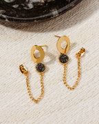 Earrings featuring gold open circles with black druzy quartz stones and dangling gold chains.
