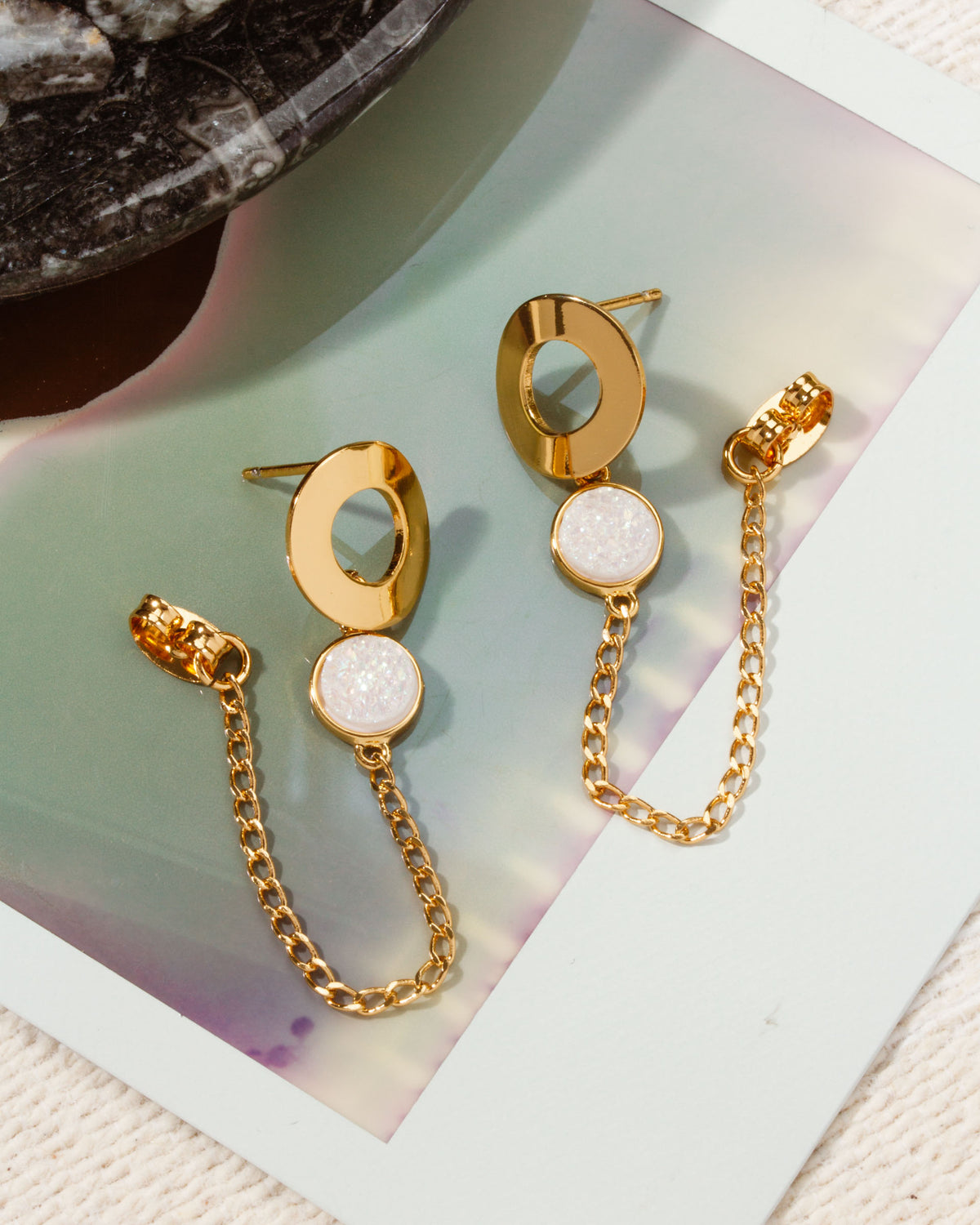 Pair of gold "Ecliptic Druzy Post Earrings" with White Druzy Quartz stones and gold chain detail.
