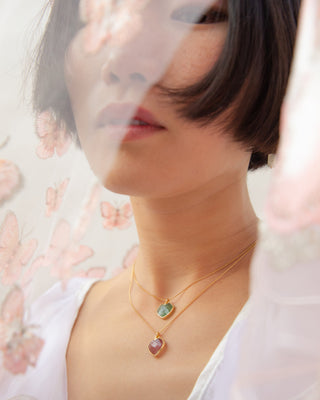 Model wearing layered emerald and Strawberry Quartz Conversation Heart necklaces