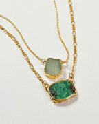 Two-tiered gold chain necklace with an emerald and light green gemstone.