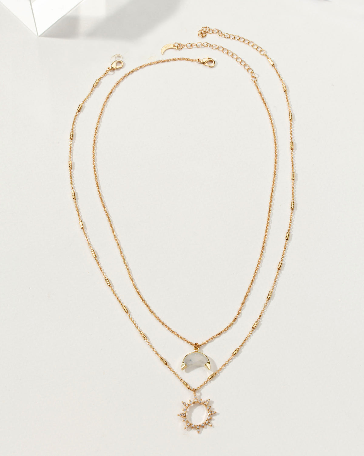Gold necklace set with a moonstone crescent moon and a sunburst pendant.
