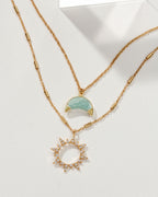 Gold necklace set with an Aquamarine moon pendant and a sun pendant with white gemstones.