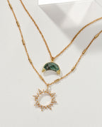 Gold necklace set with emerald crescent moon and jeweled sun pendants.