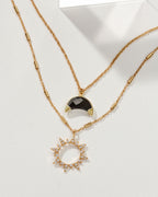 Gold necklace set with a sun pendant with stones and a moon pendant with Onyx.