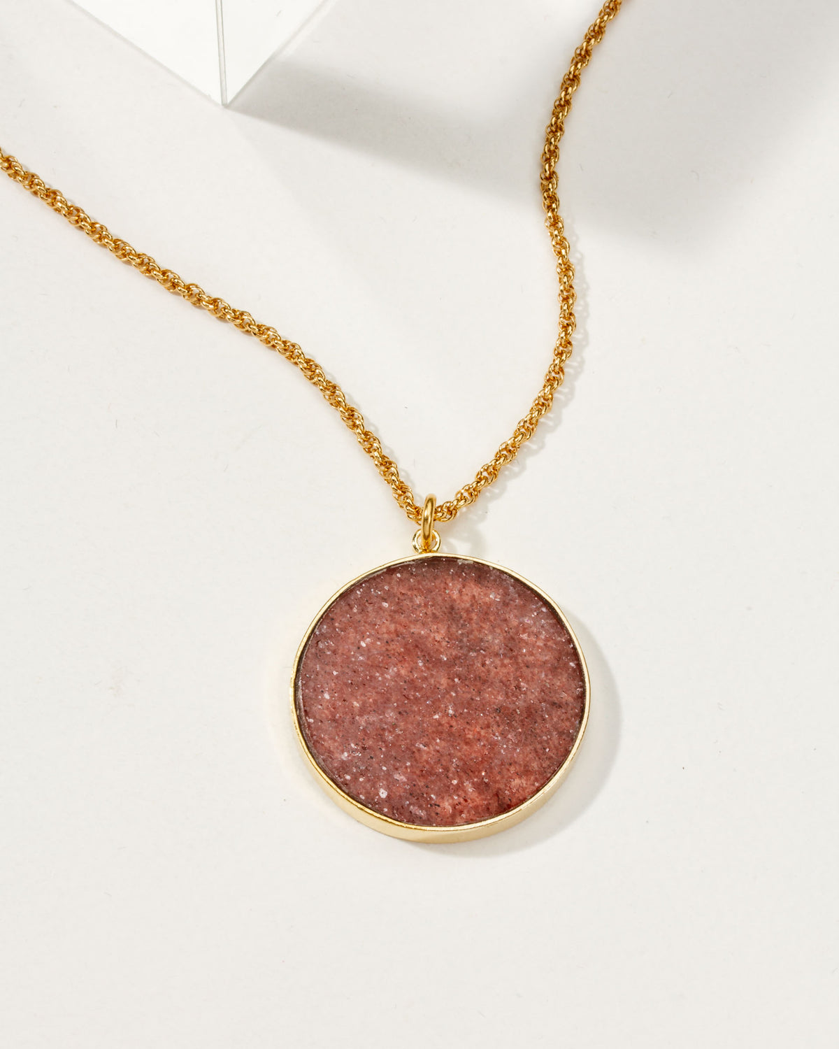 Gold chain necklace featuring a strawberry quartz medallion.