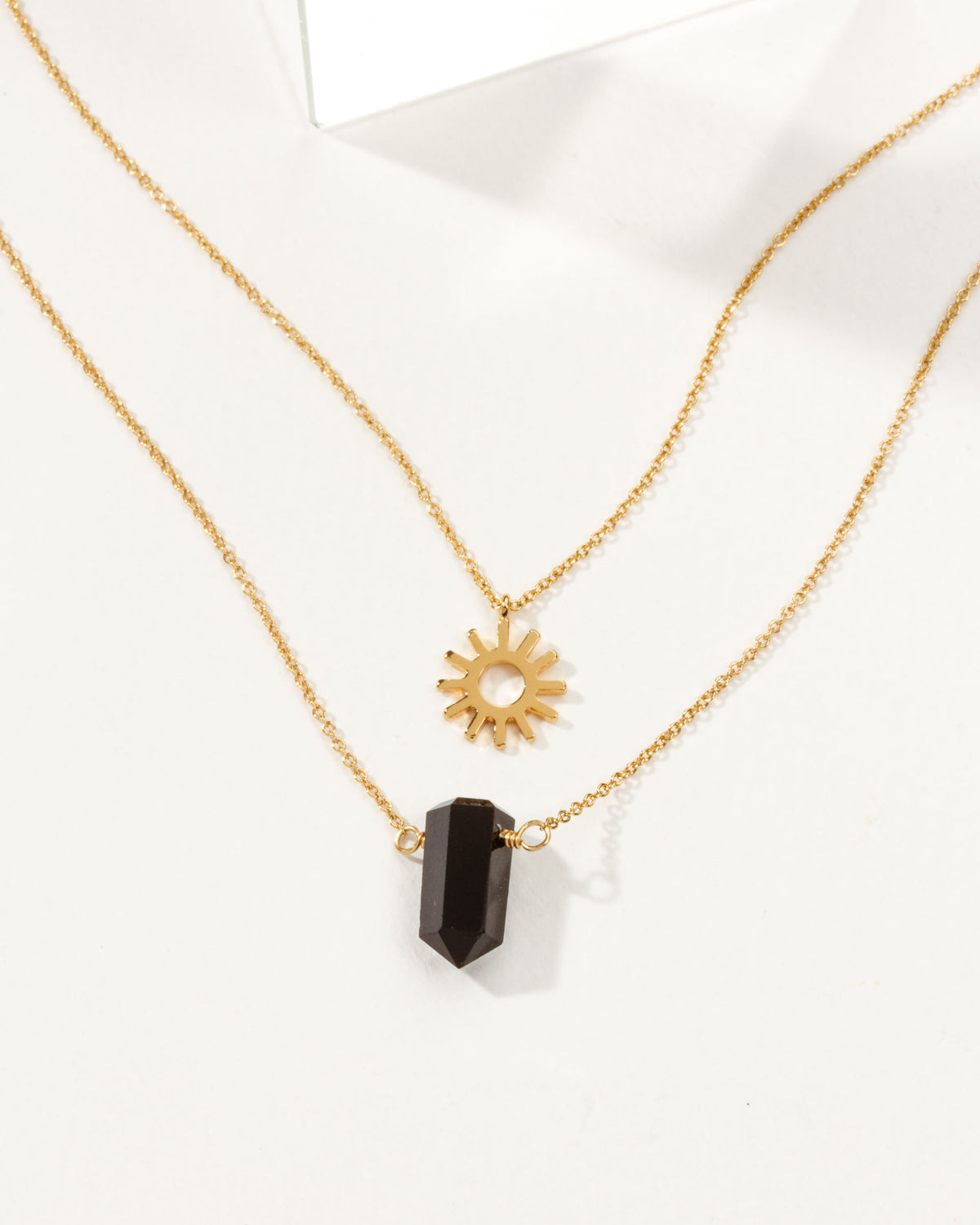 Sun Salutation necklace set with an onyx charm and a sun charm on gold chain.