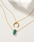 Layered gold necklaces, one with a green aventurine point and the other a crescent pendant.