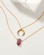 Two gold necklaces, one with a Ruby gemstone point and one crescent moon pendant.