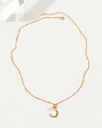 Gold chain necklace with a crescent moon charm and a small, iridescent opal.