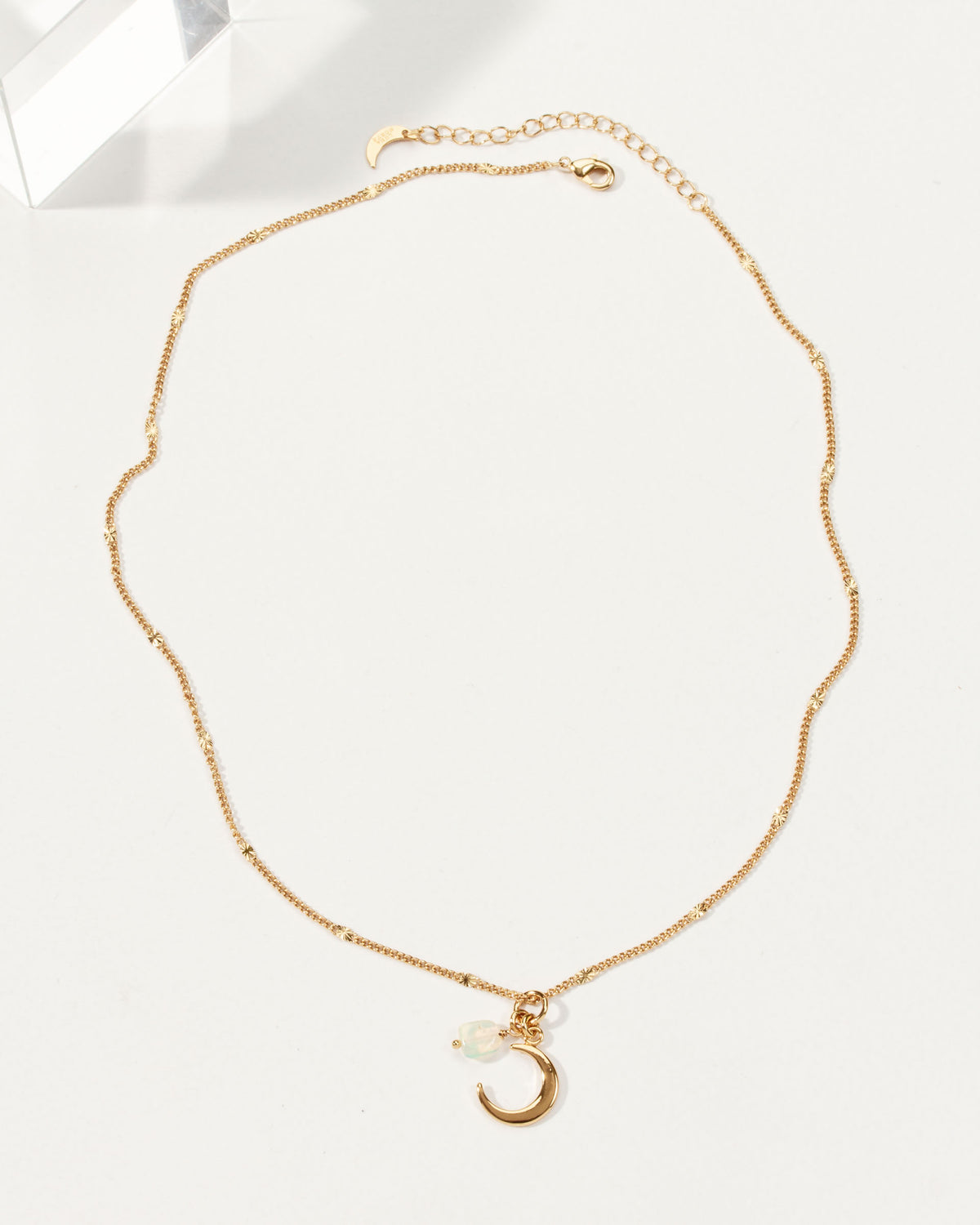Gold chain necklace with a crescent moon charm and a small, iridescent opal.