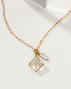 Gold chain necklace with rutilated quartz and white gemstone charms.