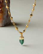 Gold chain necklace featuring an emerald green, pointed pendant.