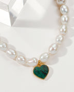 Pearl necklace with a heart-shaped Emerald pendant and gold trim.