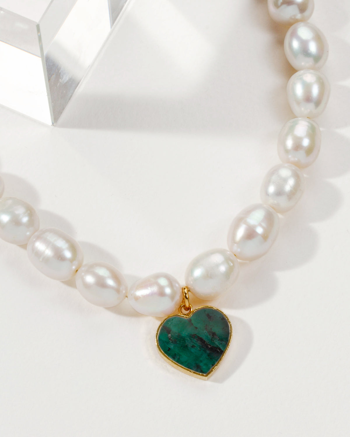 Pearl necklace with a heart-shaped Emerald pendant and gold trim.
