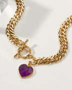 Gold chain necklace with a toggle closure and amethyst heart-shaped pendant.