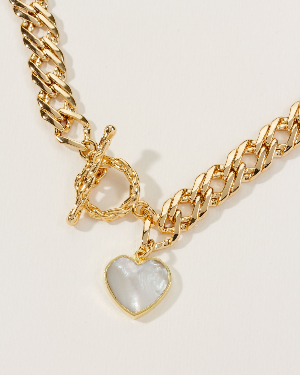 Gold chain necklace with a Mother of Pearl heart pendant and a toggle clasp.