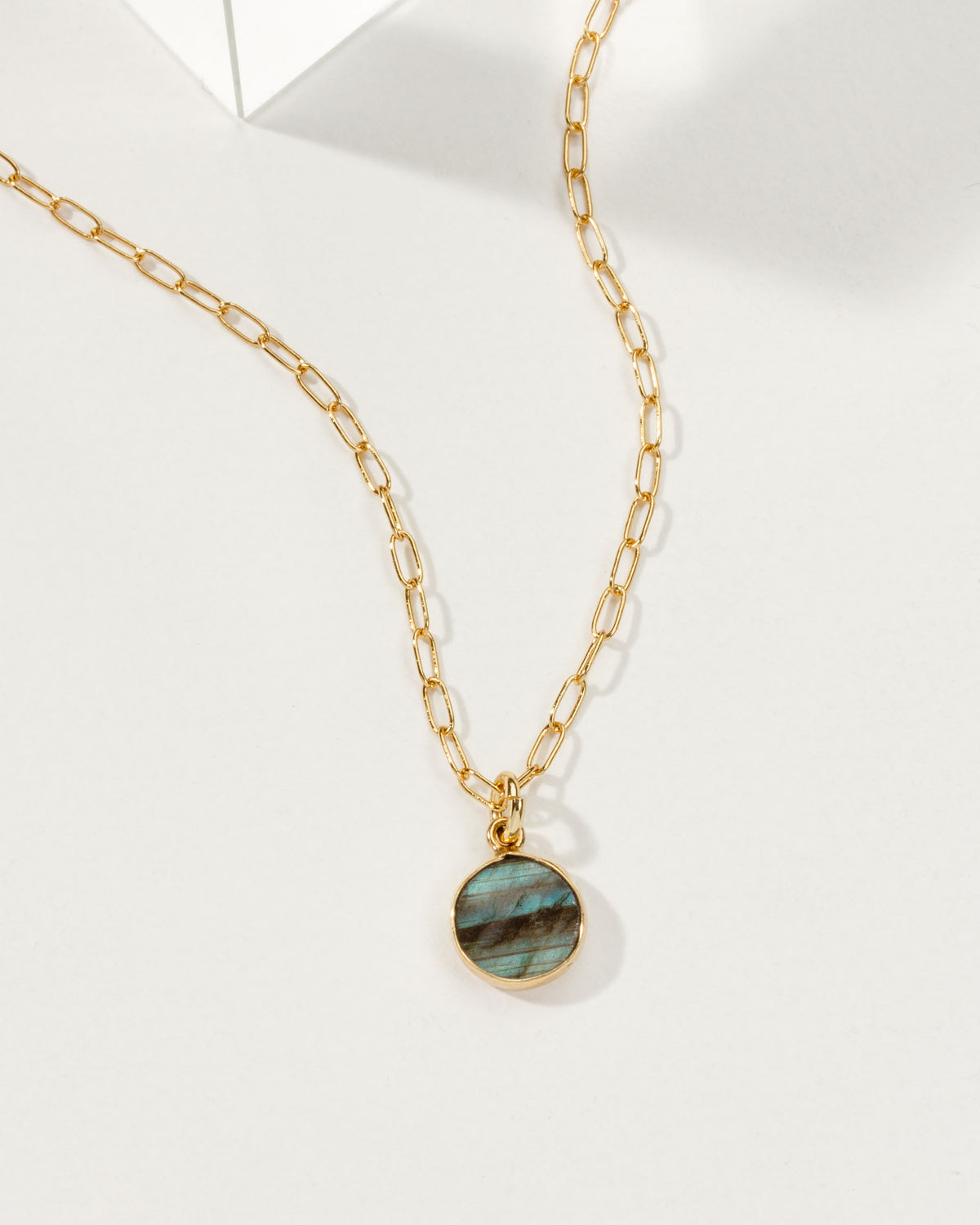 Ellipsis necklace with a gold chain and a Labradorite gemstone pendant.