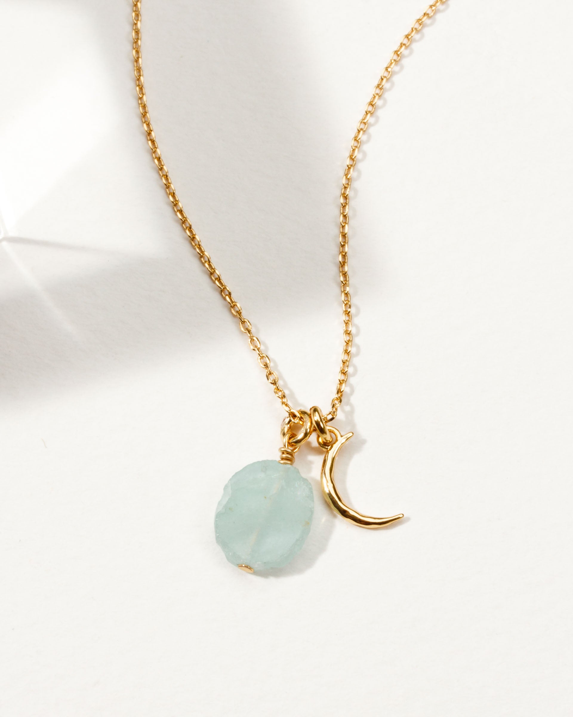 Gold necklace with a crescent moon charm and Aquamarine gemstone.