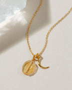 Gold necklace with a crescent moon charm and Citrine gemstone.