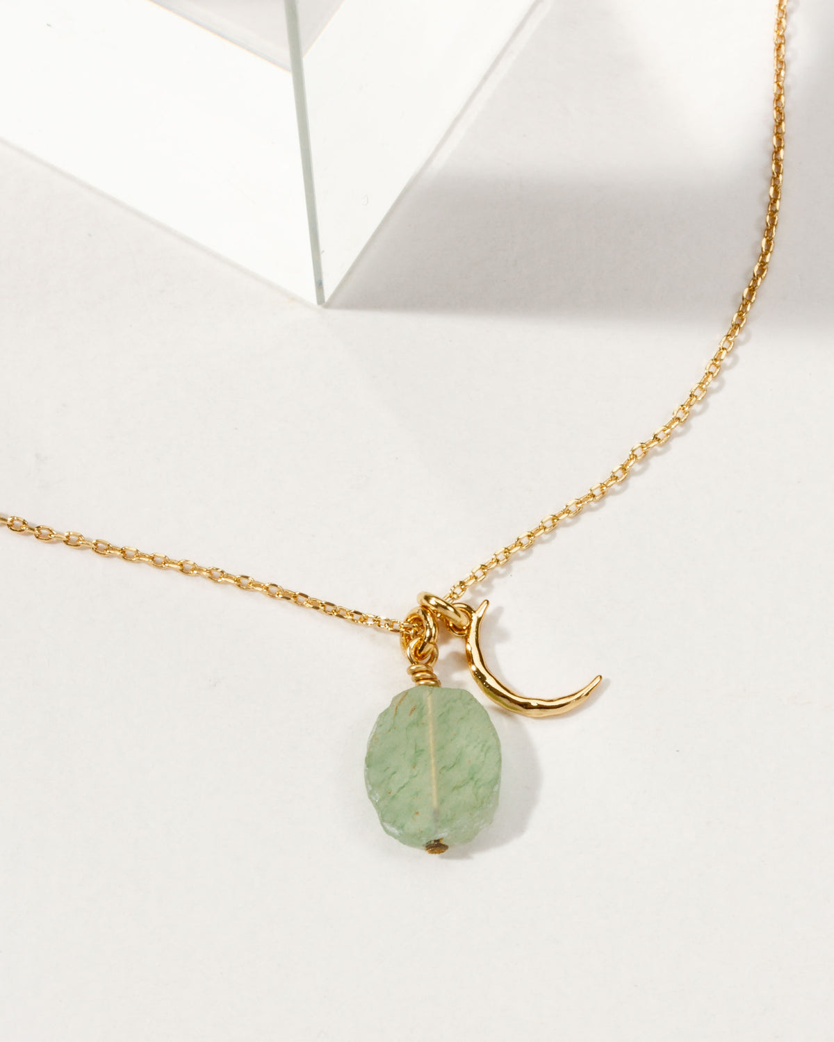 Gold necklace with a crescent moon charm and a green aventurine gemstone.