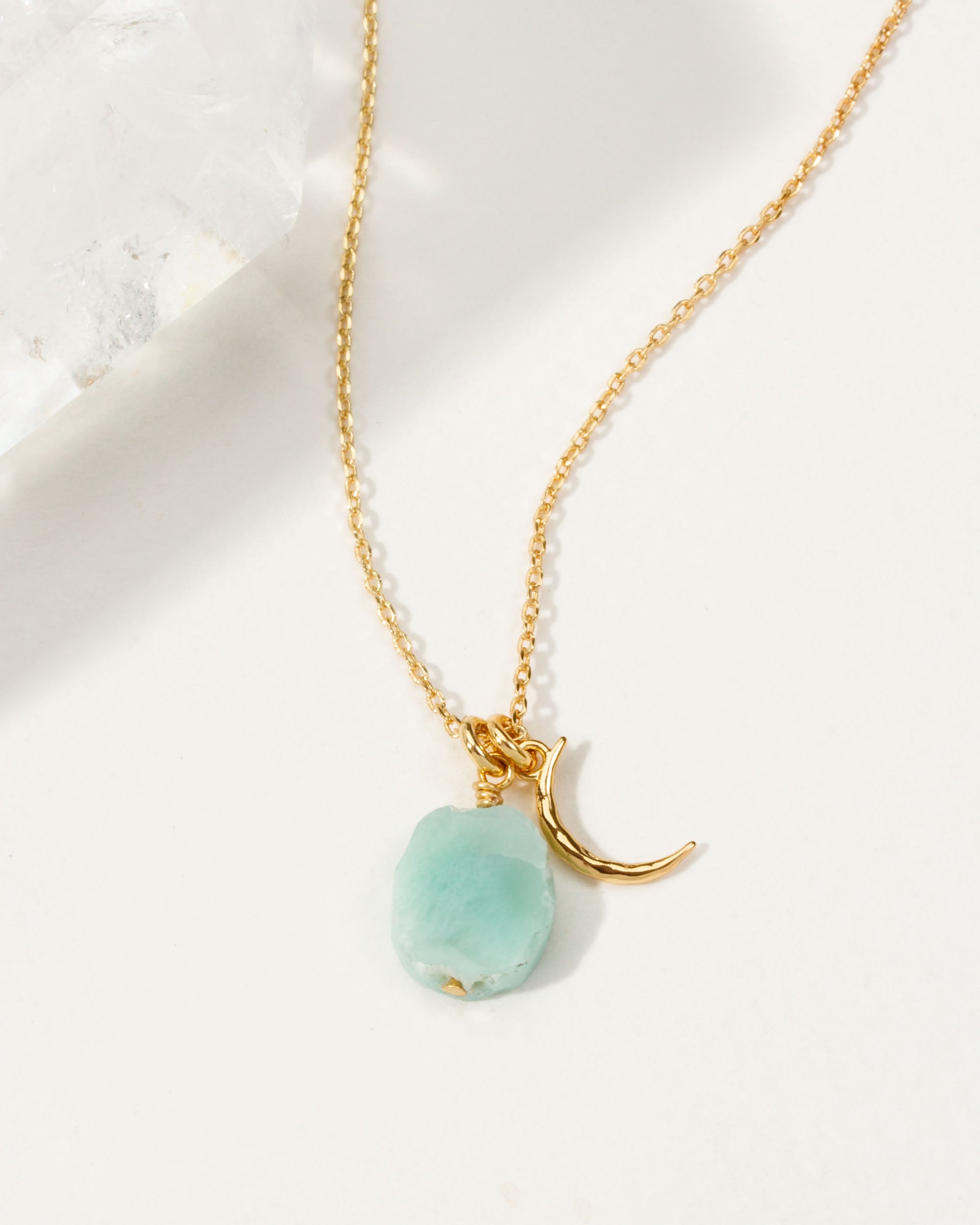 Gold necklace with a crescent moon charm and an Aquamarine gemstone.
