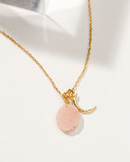 Gold chain necklace with a crescent moon charm and a Rose Quartz gemstone.
