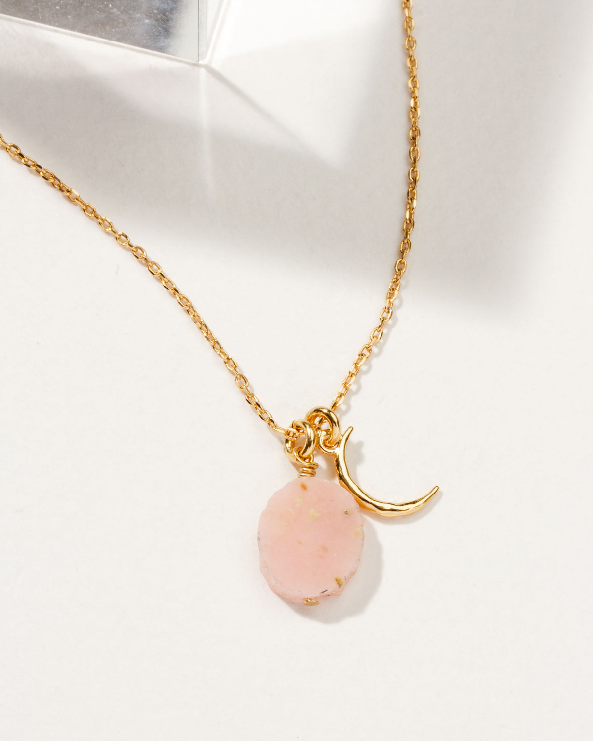 Gold chain necklace with a crescent moon charm and a Rose Quartz gemstone.