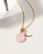 Gold chain necklace with a crescent moon charm and a Rose Quartz gemstone.