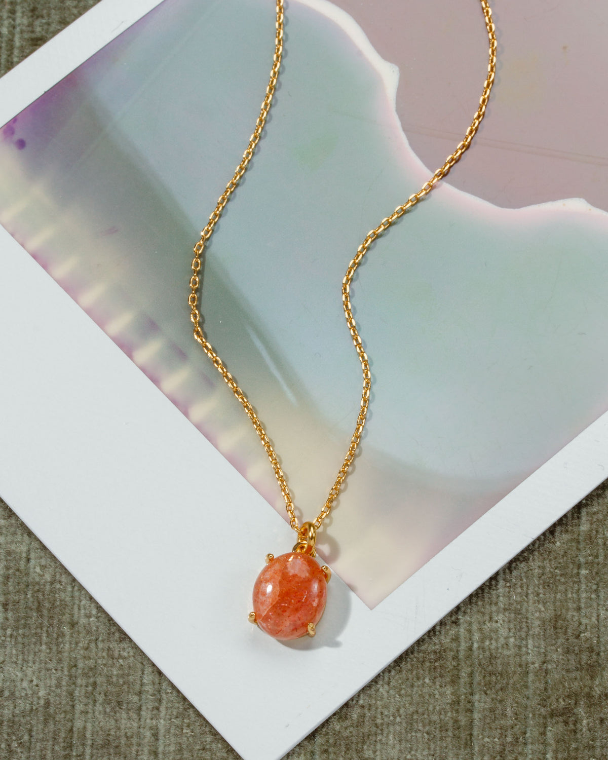 Gold chain necklace with a Sunstone pendant.