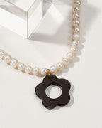 Pearl necklace with a black flower pendant.