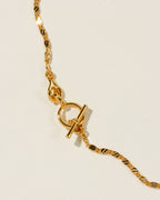 Close-up of the Adorned Toggle Necklace, showing the golden chain and clasp.