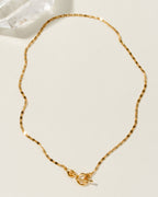 Golden Adorned Toggle Necklace with a unique chain pattern is displayed on a neutral background.