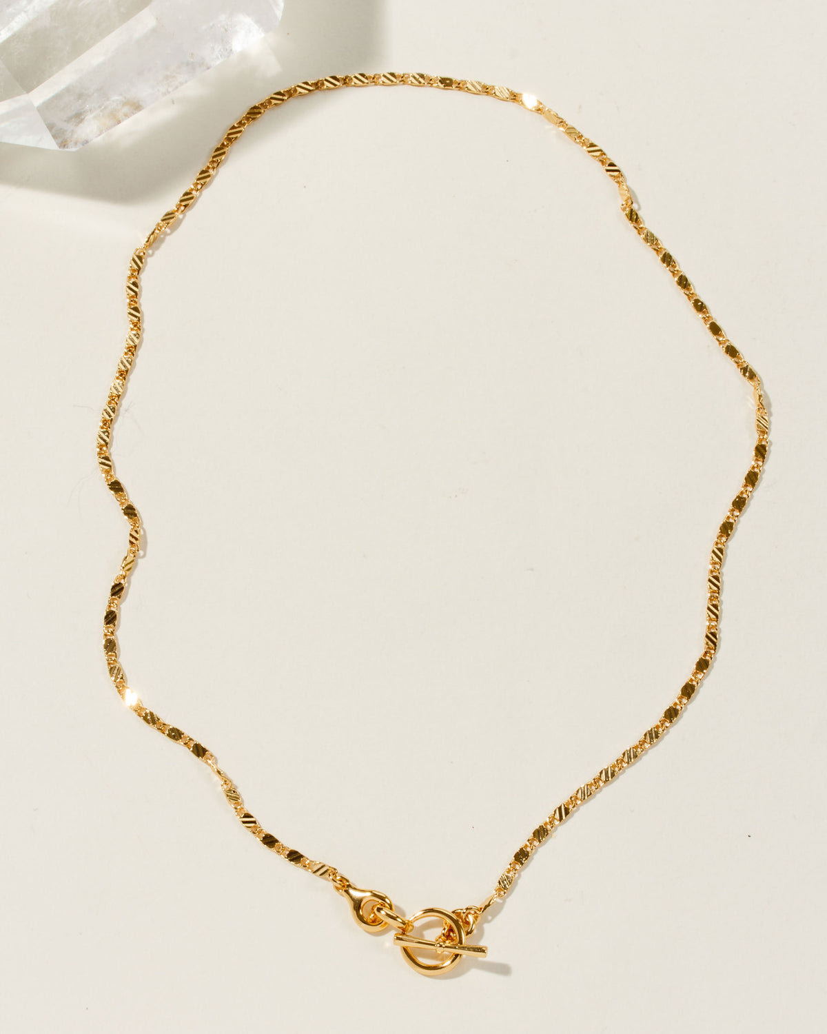 Golden Adorned Toggle Necklace with a unique chain pattern is displayed on a neutral background.