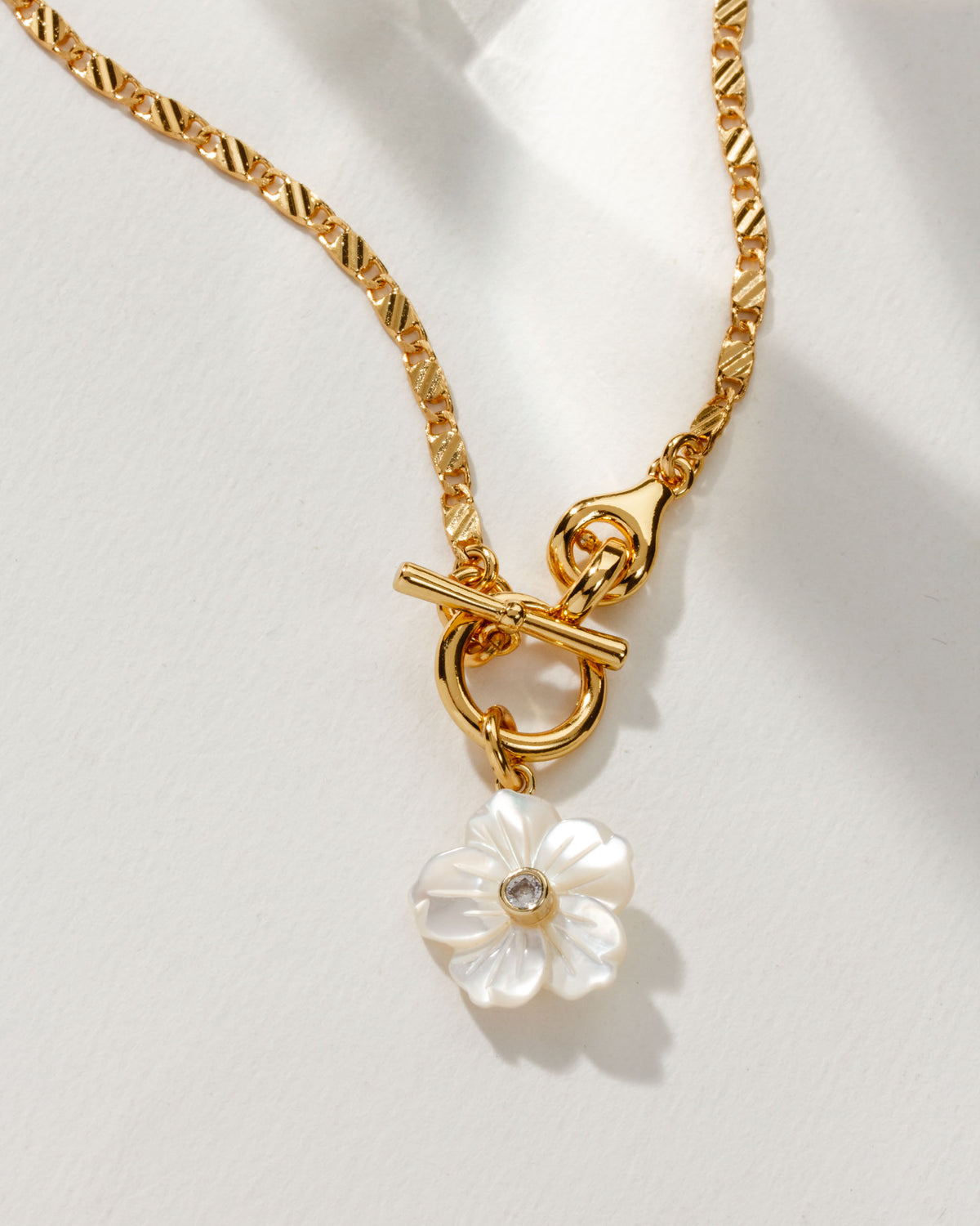 Gold chain necklace featuring a mother of pearl flower pendant with a CZ center.