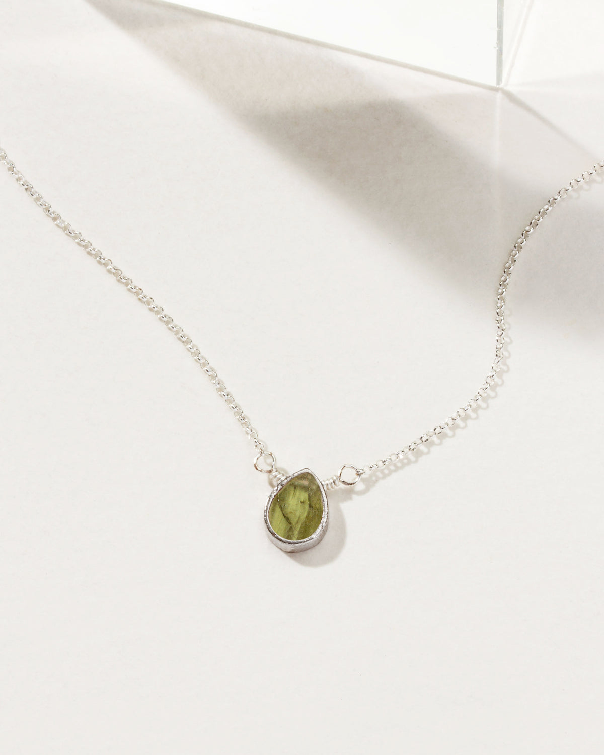 Silver plated necklace with a green gemstone pendant.