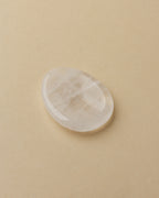 A smooth quartz stone with a slight indent, placed on a white surface.